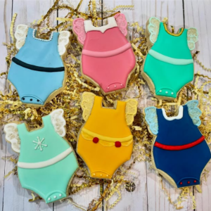Set of sugar cookies shaped like baby onesies, decorated with Disney princess dress designs