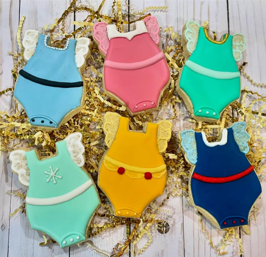 Set of sugar cookies shaped like baby onesies, decorated with Disney princess dress designs